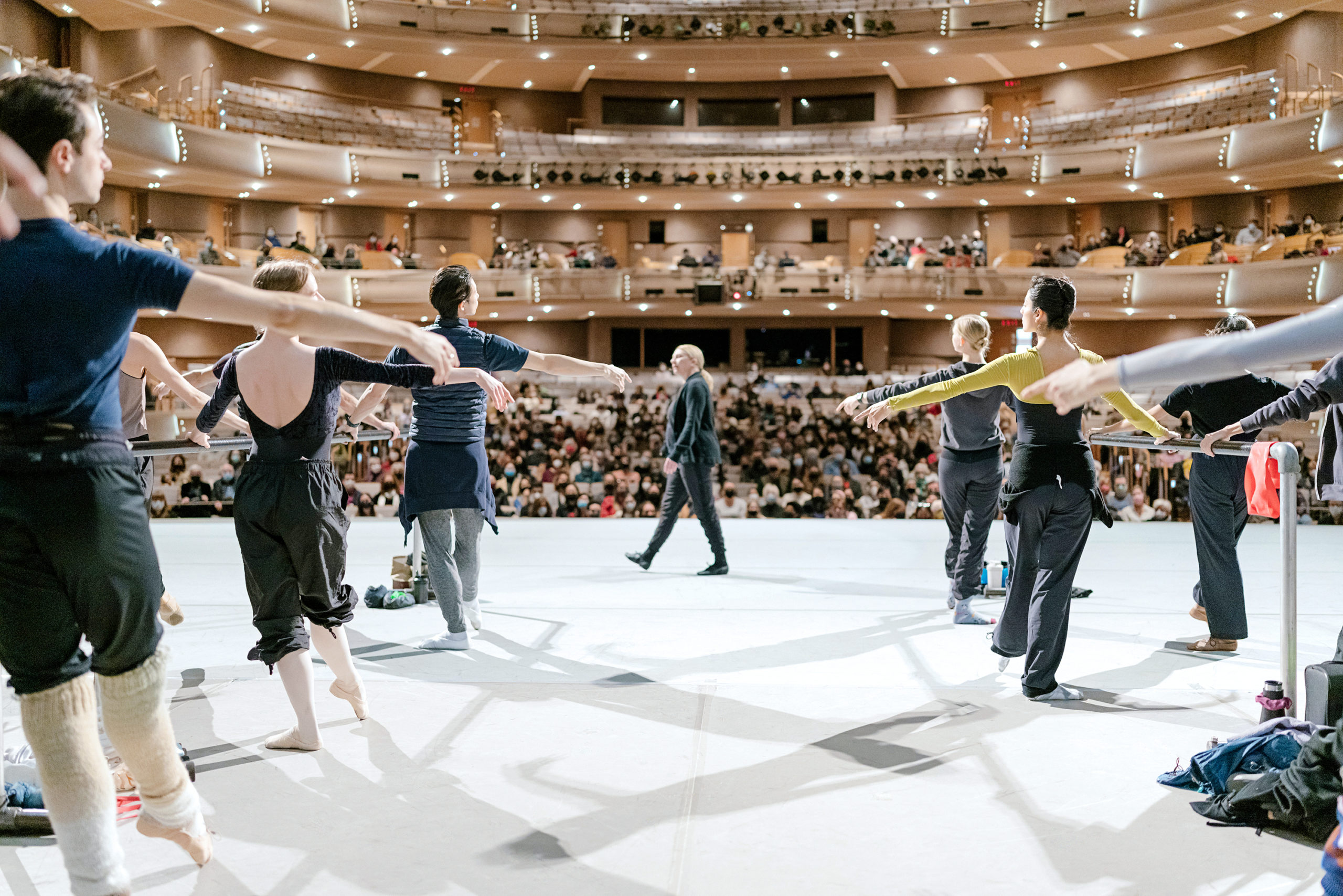 a group of dancers at the barre in front of an audience