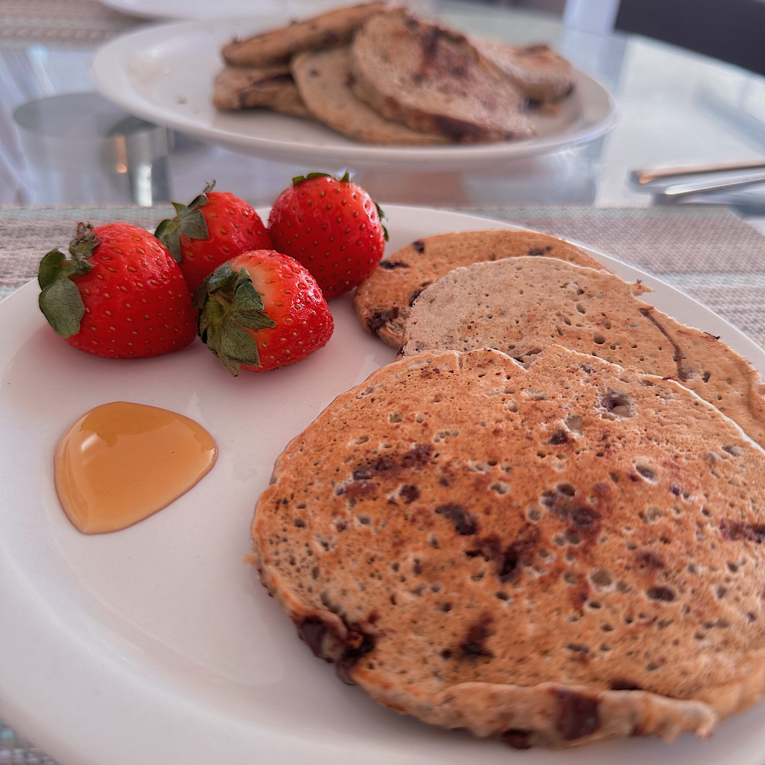 three pancakes sitting on a white plate with strawberries and syrup