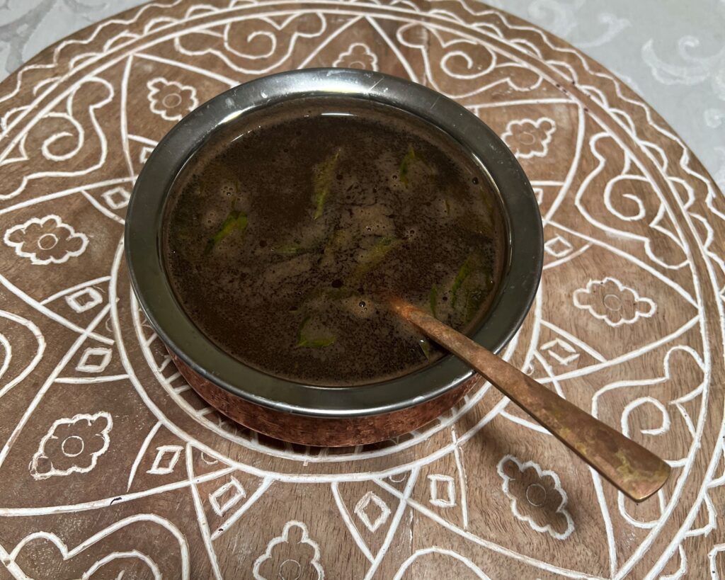 a metal bowl with a dark soup inside