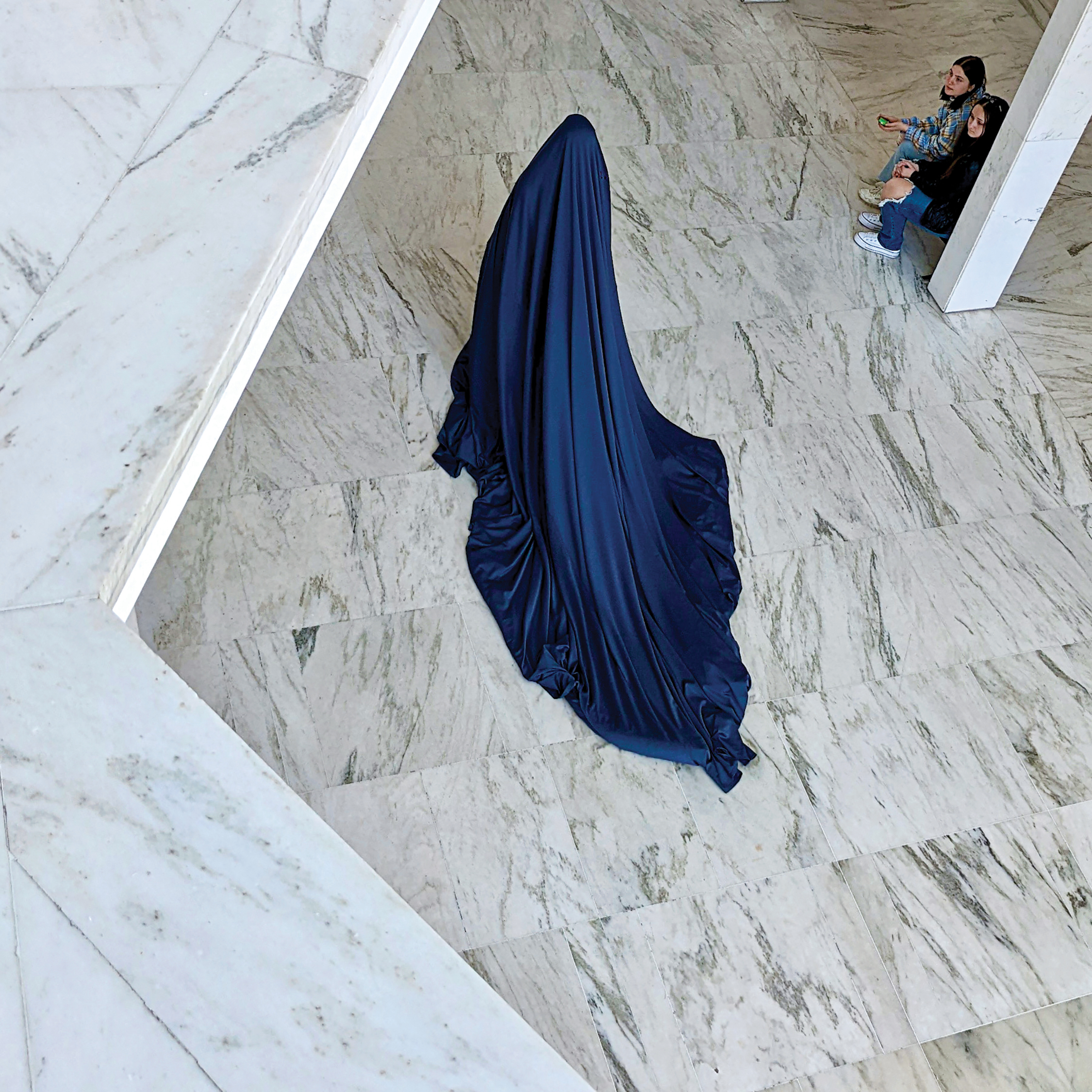 dancer covered in blue sheet dancing on marbled floor