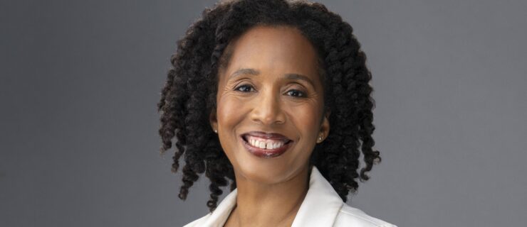 an african american woman wearing black and a white jacket smiling at the camera