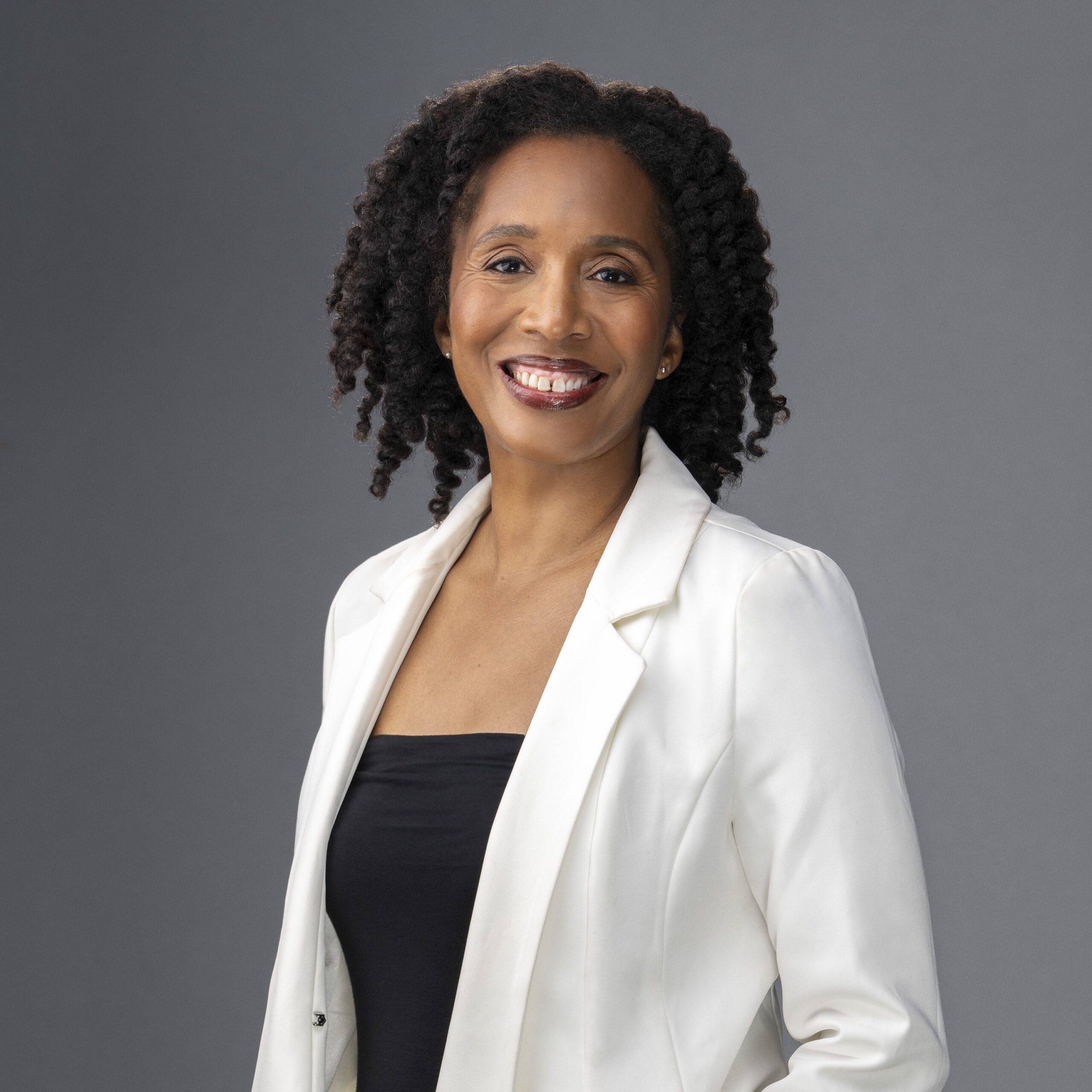 an african american woman wearing black and a white jacket smiling at the camera