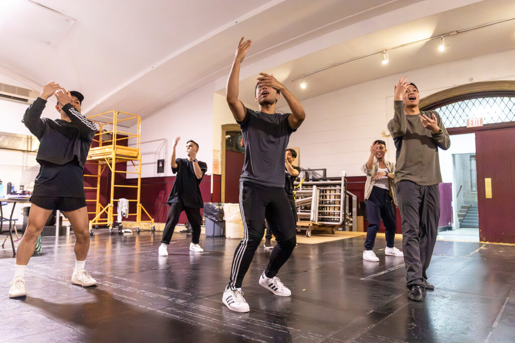 a group of dancers reaching up to the right while rehearsing