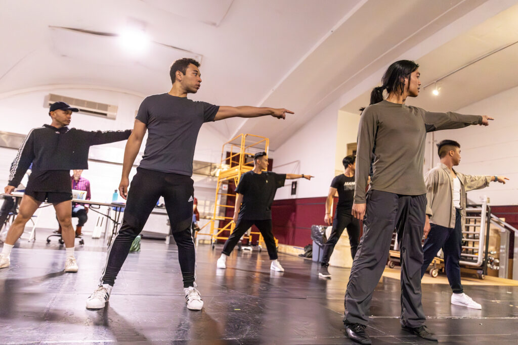 a group of dancers pointing to the left while rehearsing