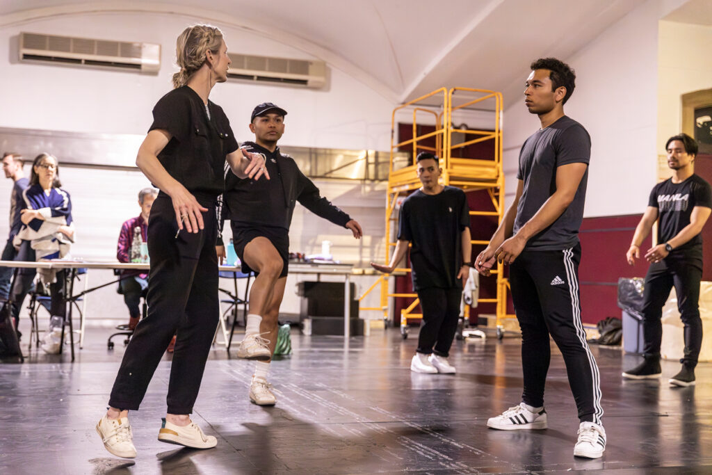 a blonde woman giving talking to dancers in rehearsal