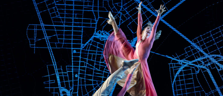 a female dancer reaching up and extending her leg side; a male dancer laying on the floor and kicking over his head