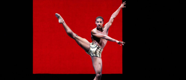 a male dancer wearing short extending his leg a la seconde with his arms going the opposite way