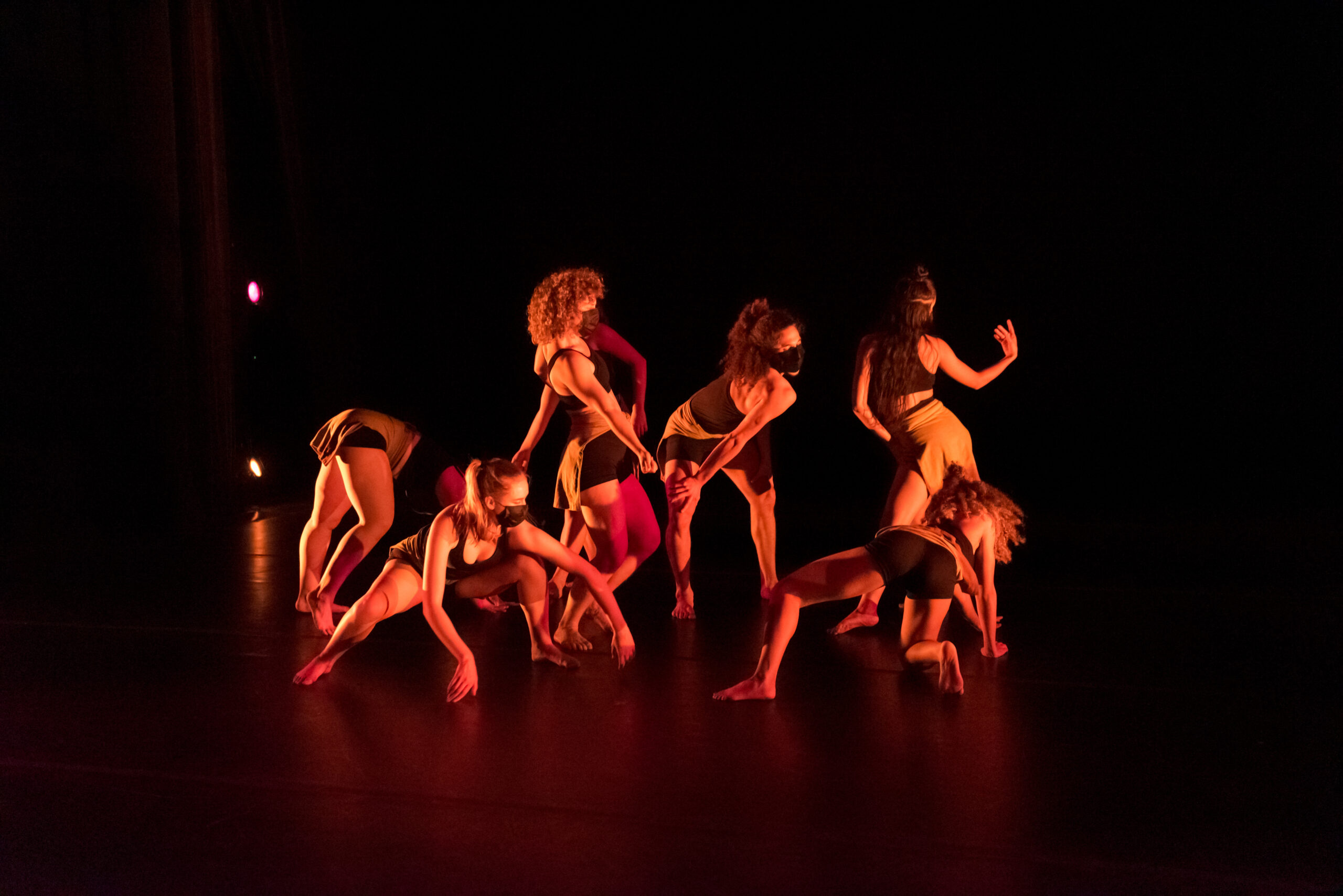 a group of female dancers performing a variety of steps wearing black masks and costumes on stage