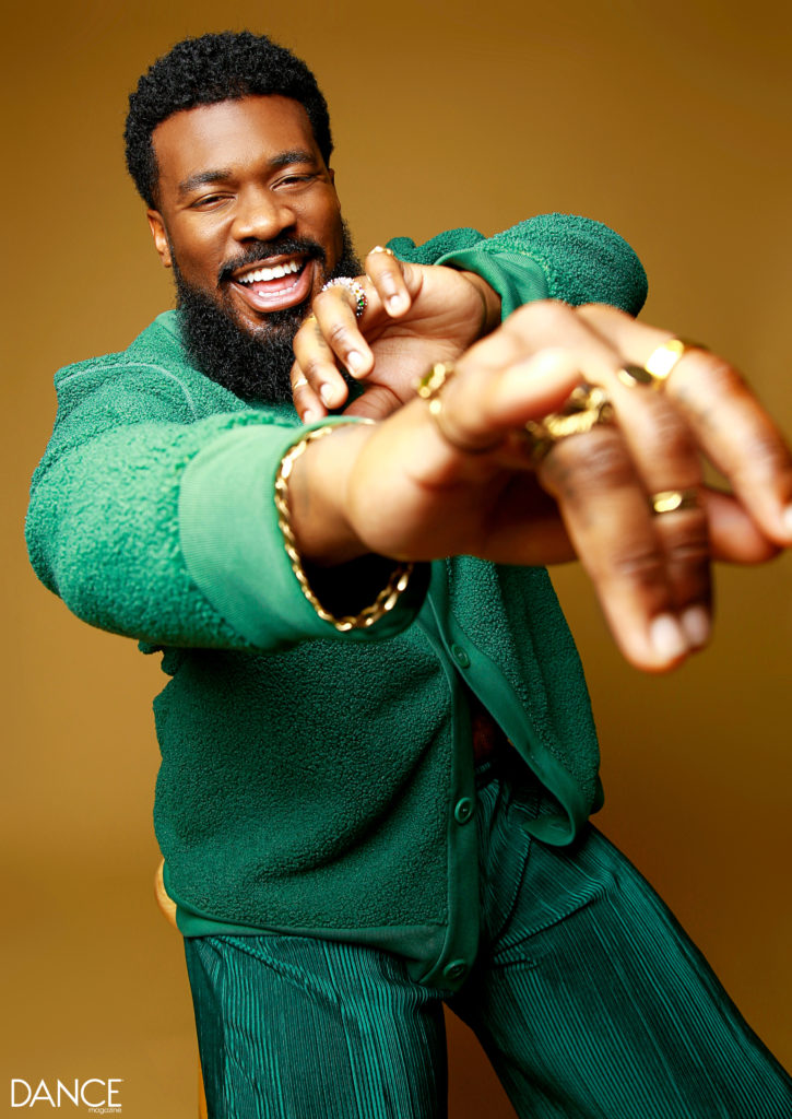 Close-up of JaQuel Knight with his hands towards the camera, showing off many rings, smiling big