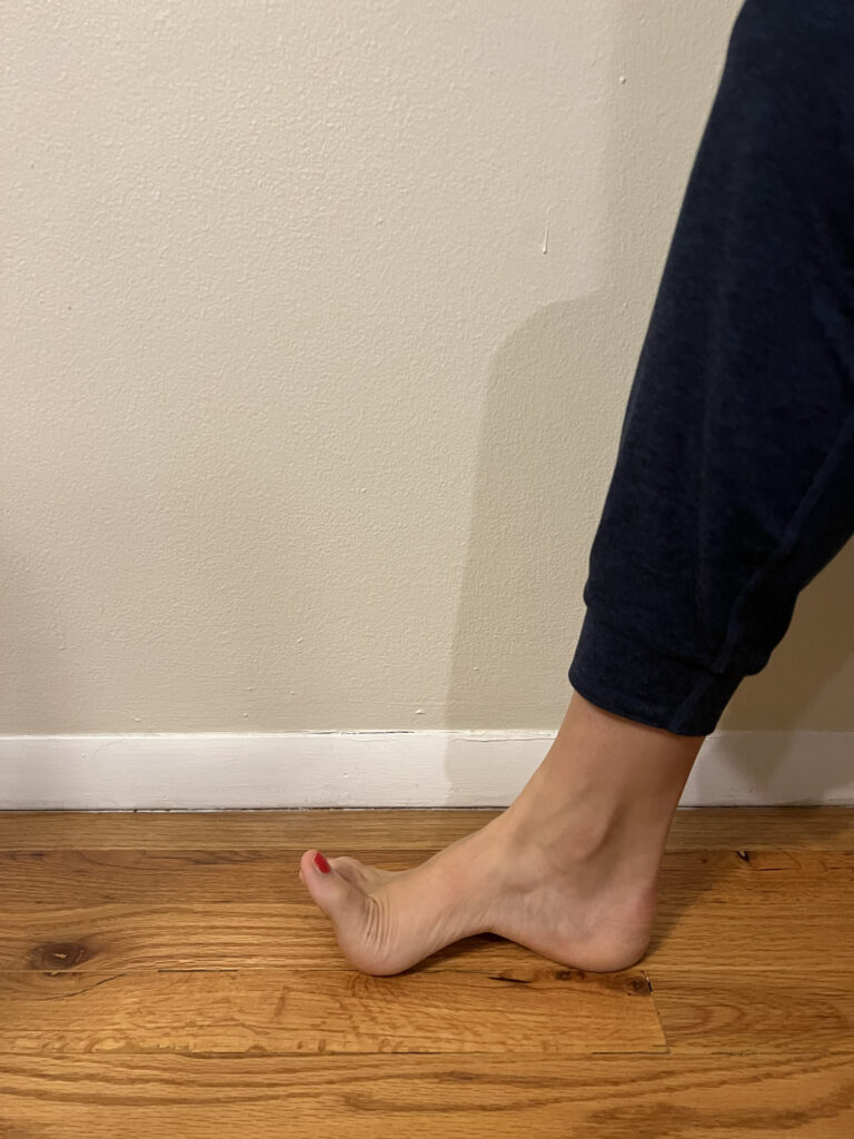 a dancer with their foot in front of them as they lift their toes off the ground