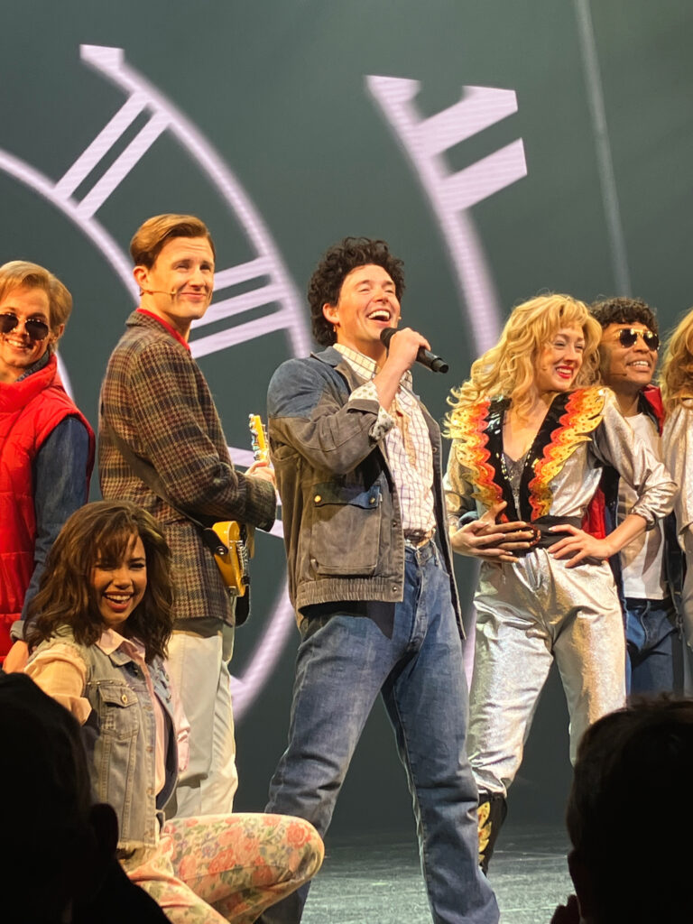 a male performer holding a microphone surrounded by other performers