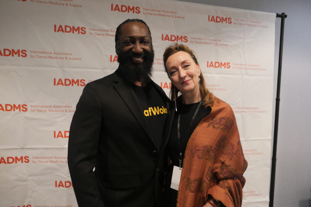 a man and woman standing together in front of a photo backdrop