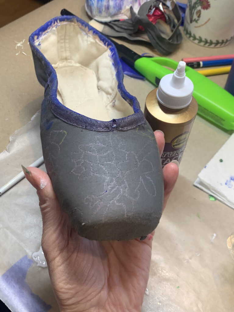 a pointe shoe painted black with a floral design