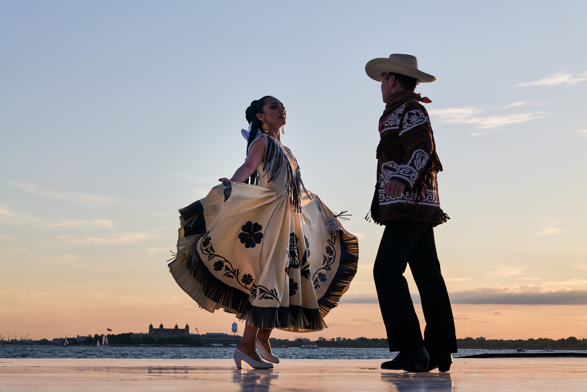 a male and female dancer dressed in western style clothing dancing on an outdoor stage