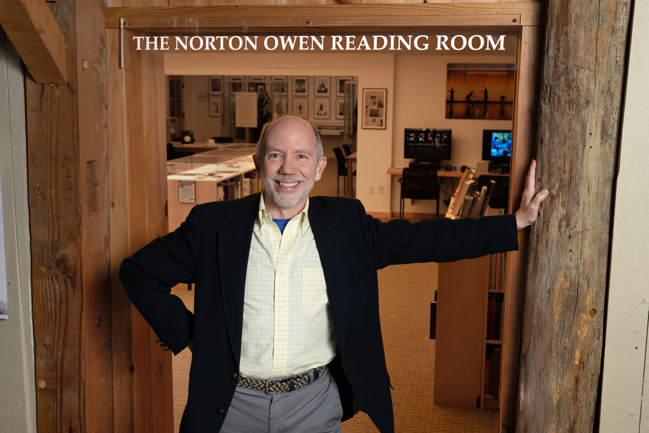 a man smiling at the camera with one hand against the wall