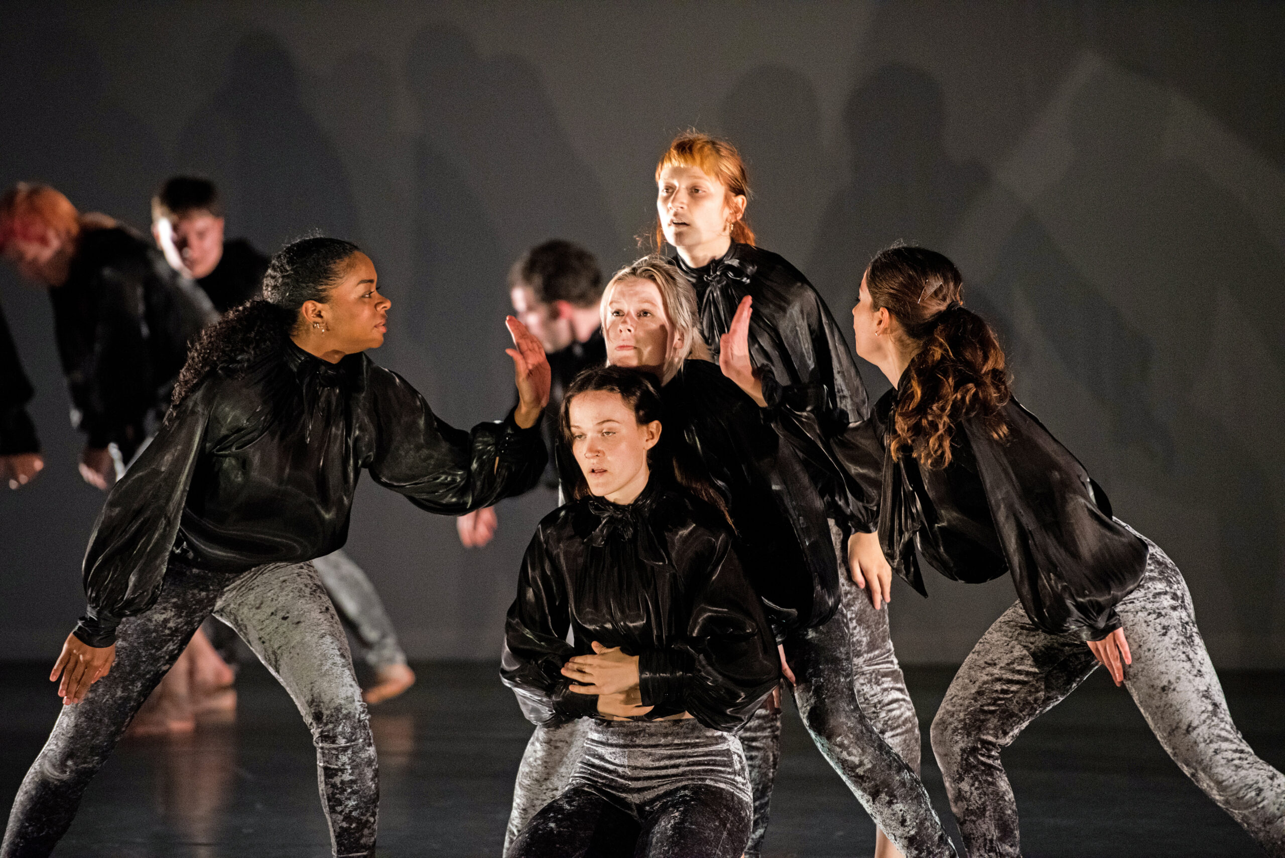 a group of female dancers on stage, all wearing black jackets