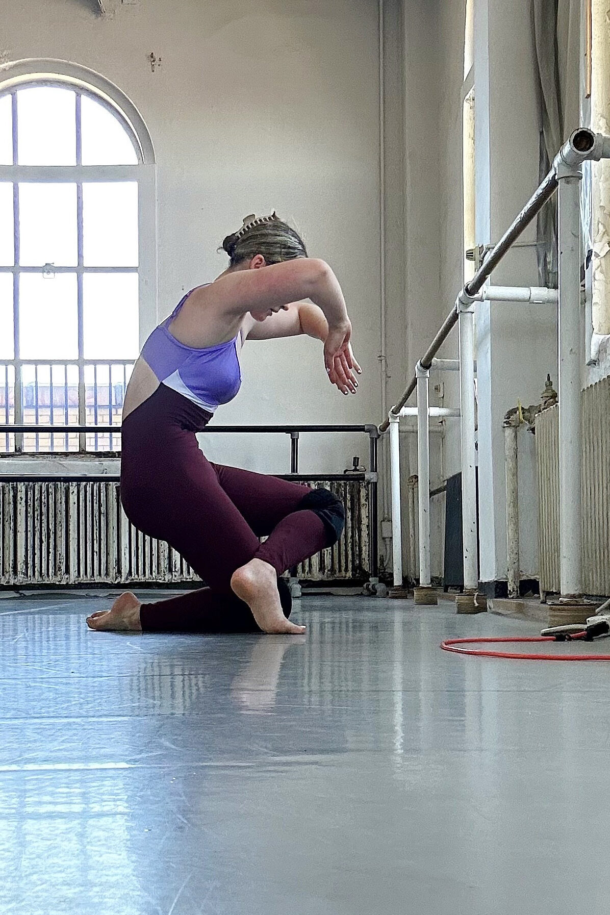 a female student kneeling and contracting on the floor of a studio