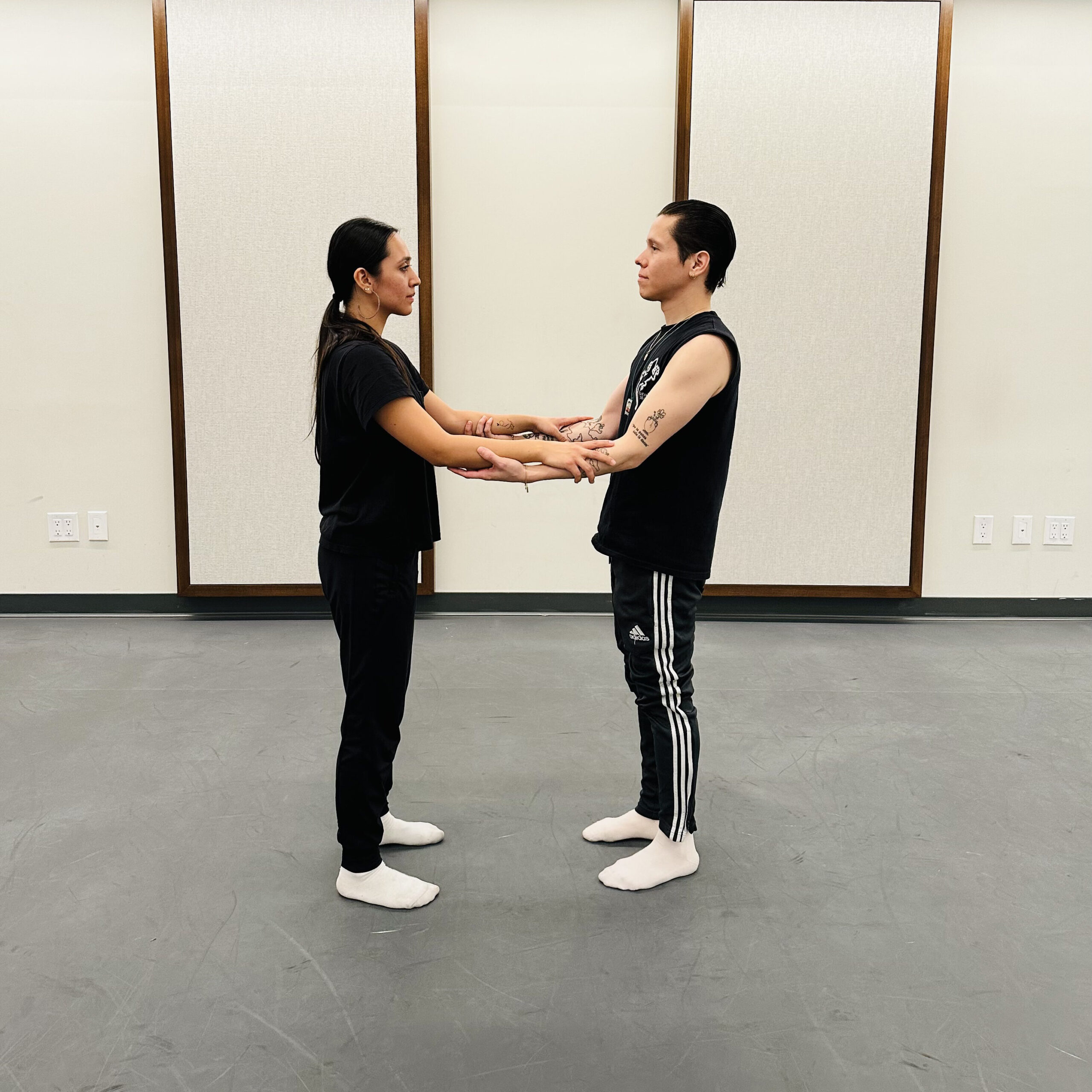 a male and woman facing each other while holding each other's forearms