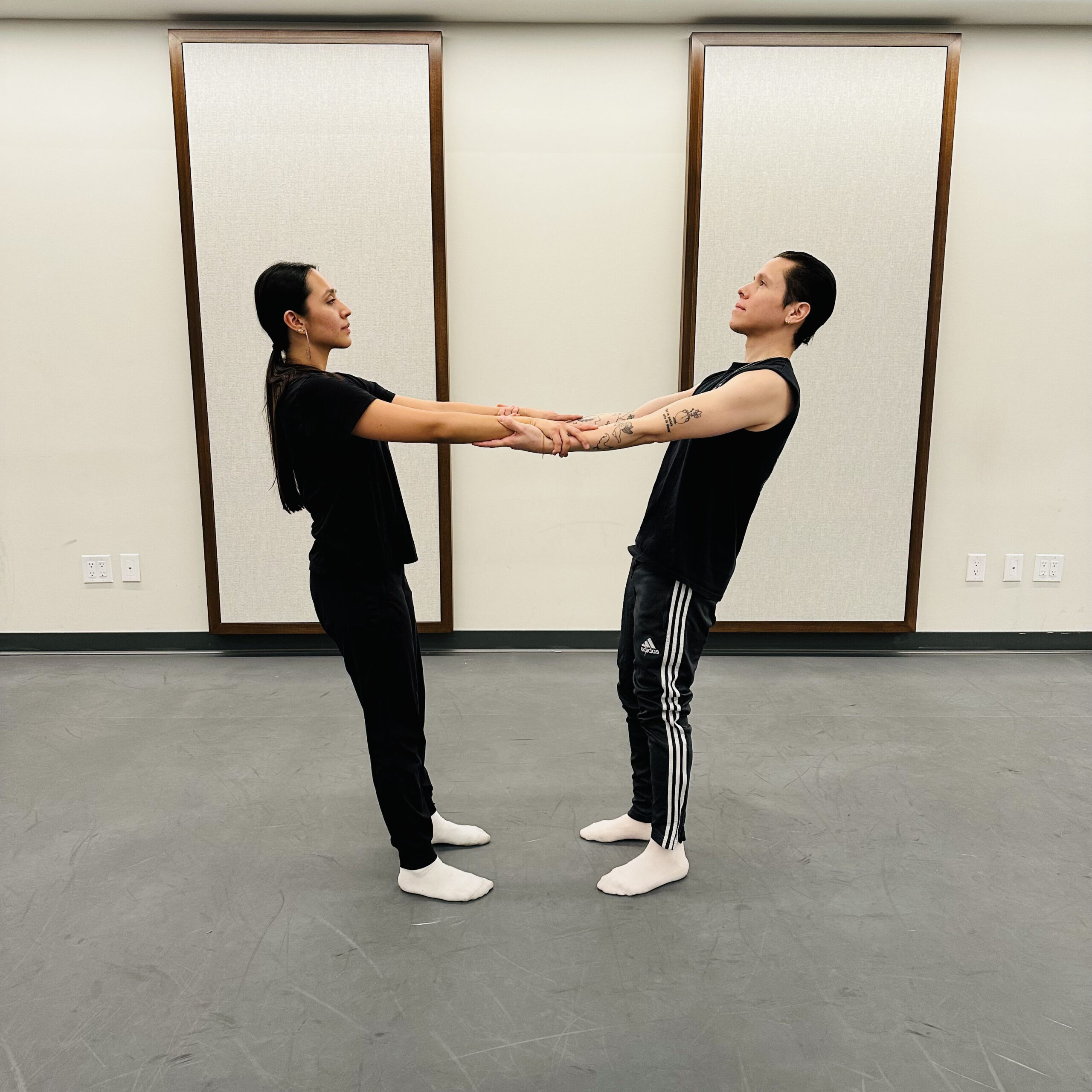 a male and woman facing each other while holding each other's forearms and leaning backwards