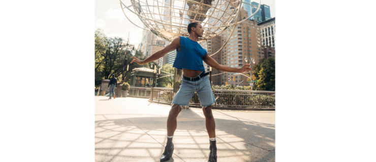 a male dancer wearing jean shorts, a tank top, a heeled boots, dancing on a sidewalk