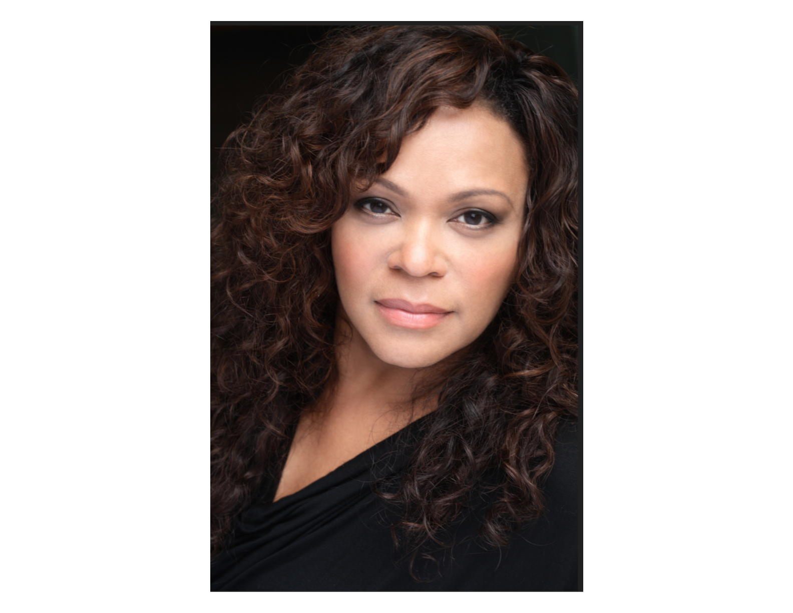 a woman with curly, long hair looking at the camera