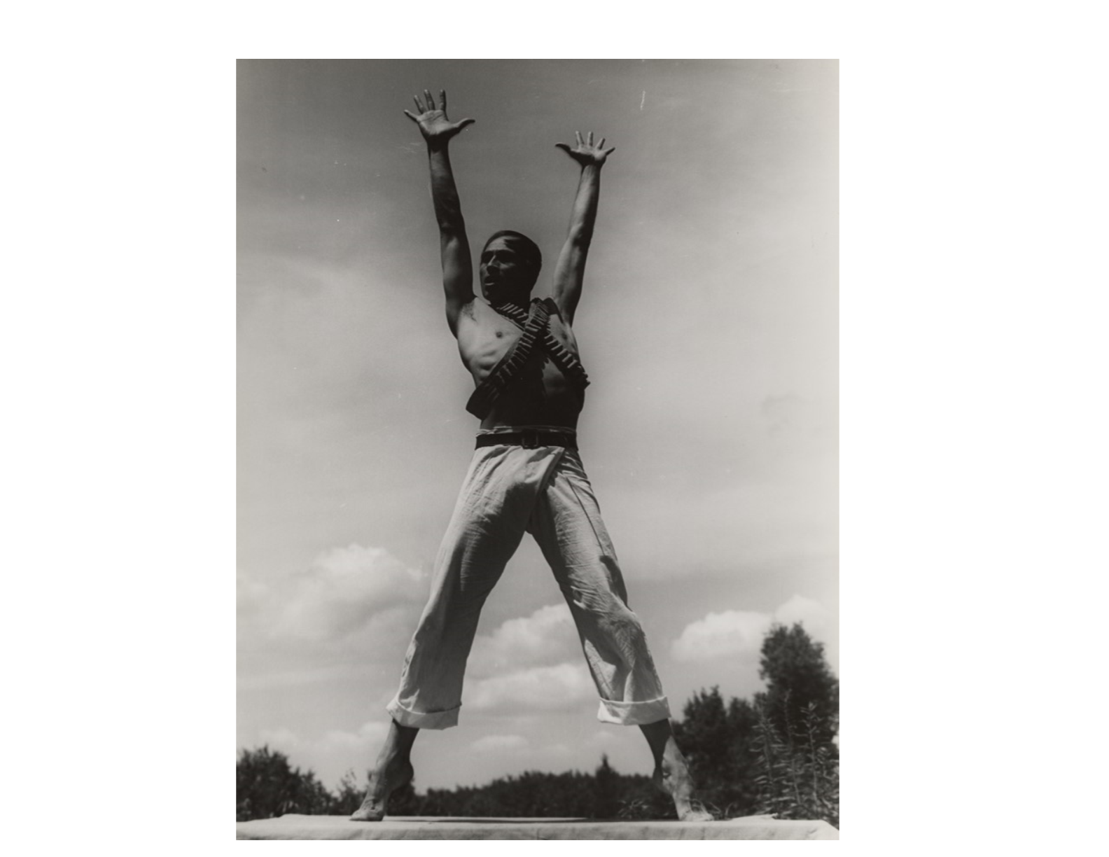 a male dancer standing on an outdoor stage lifting his arms over his head